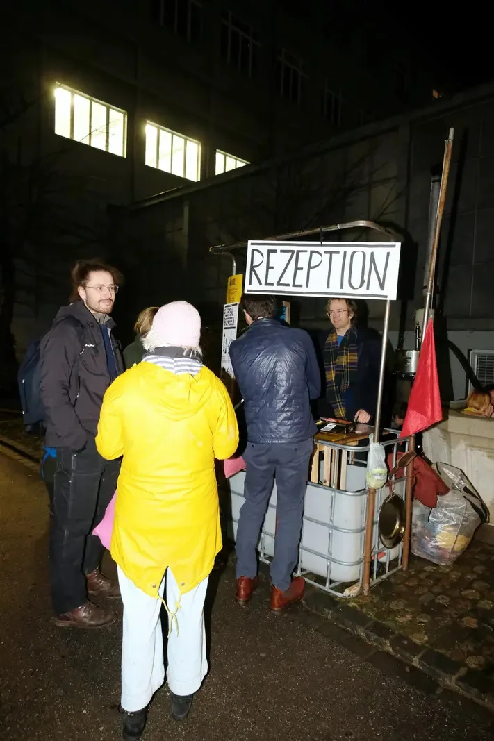 Man sieht eine mobile Rezeption und Menschen, die davor stehen.